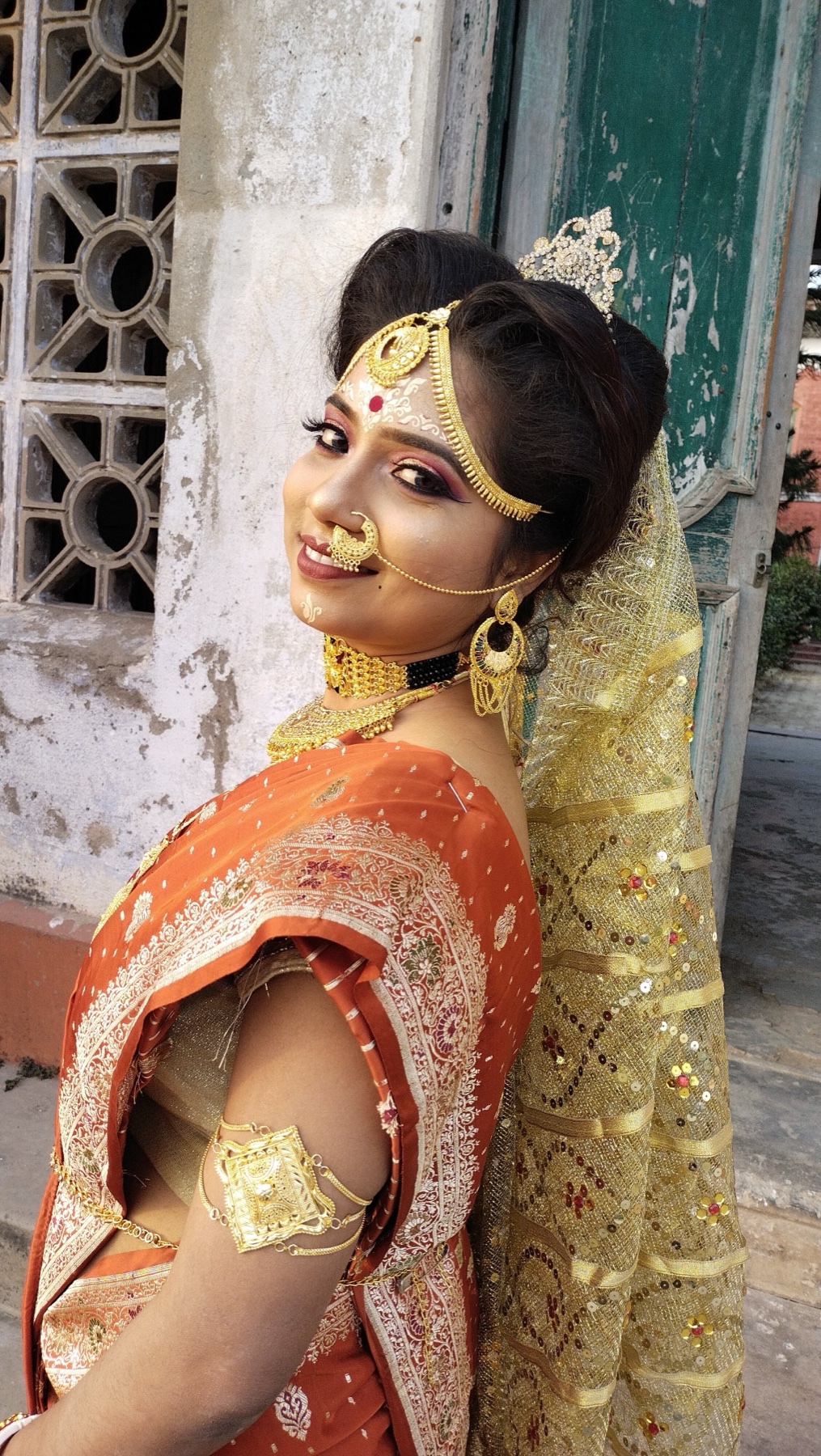 Traditional Bengali bride in an orange saree with bridal makeup and jewellery