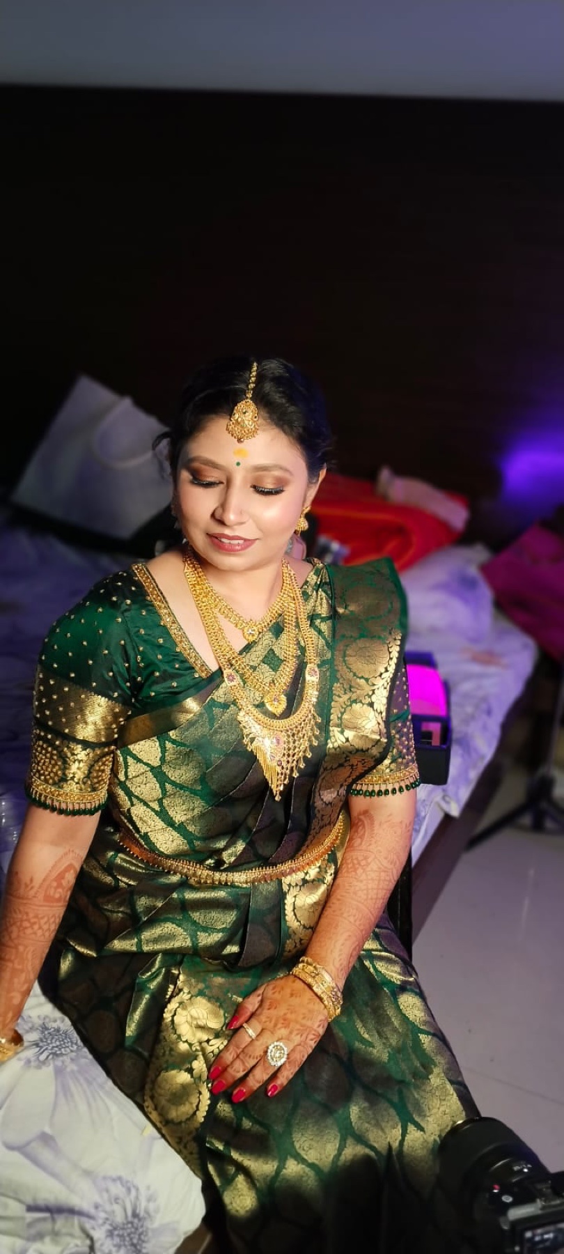 Bride in an emerald and gold saree with luminous makeup and a sleek updo