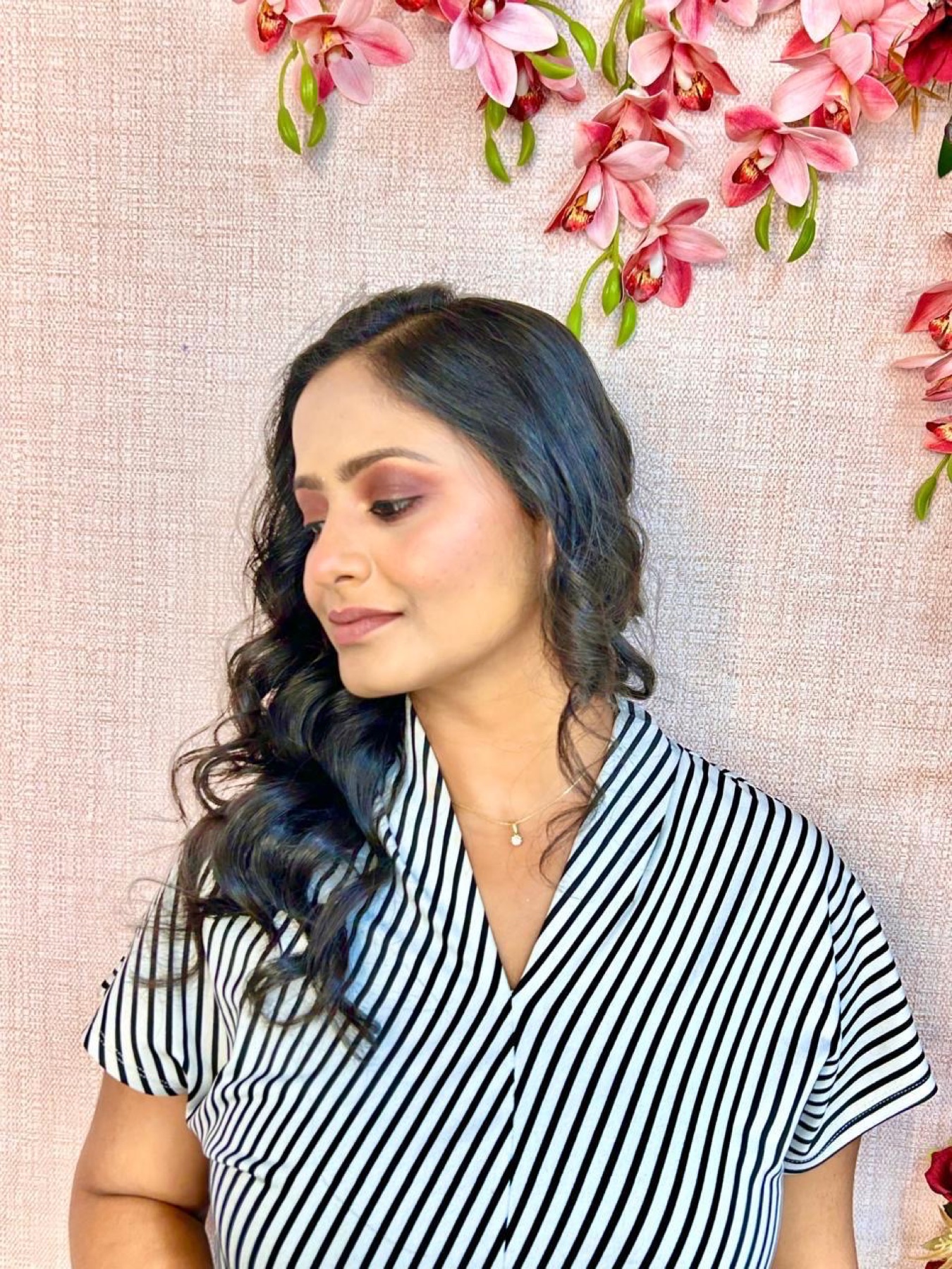 Soft rose-toned makeup with side-swept curls for an elegant occasion look
