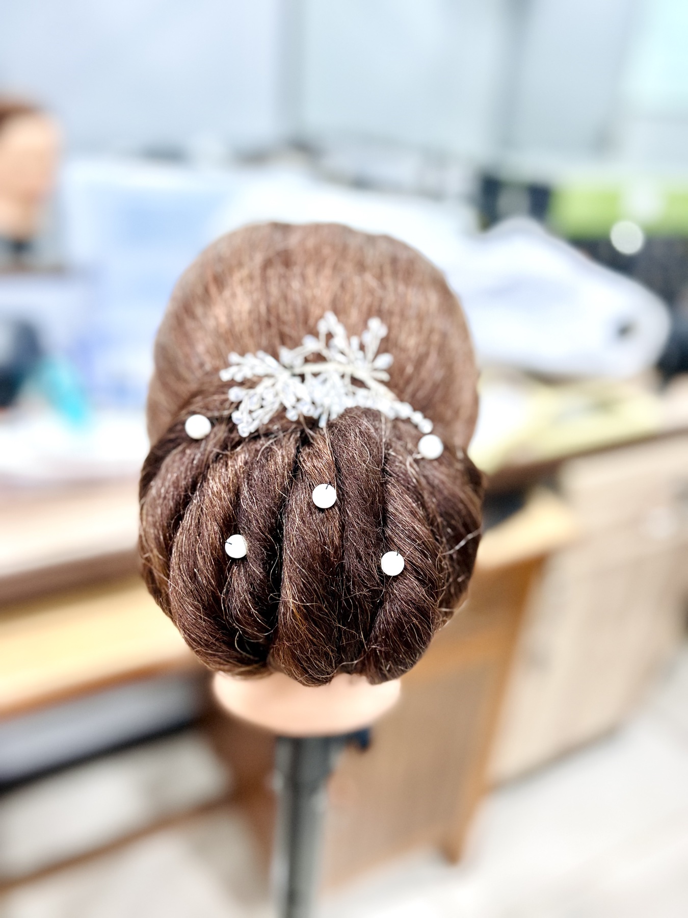 Detailed bridal bun decorated with pearl pins and a silver hair ornament