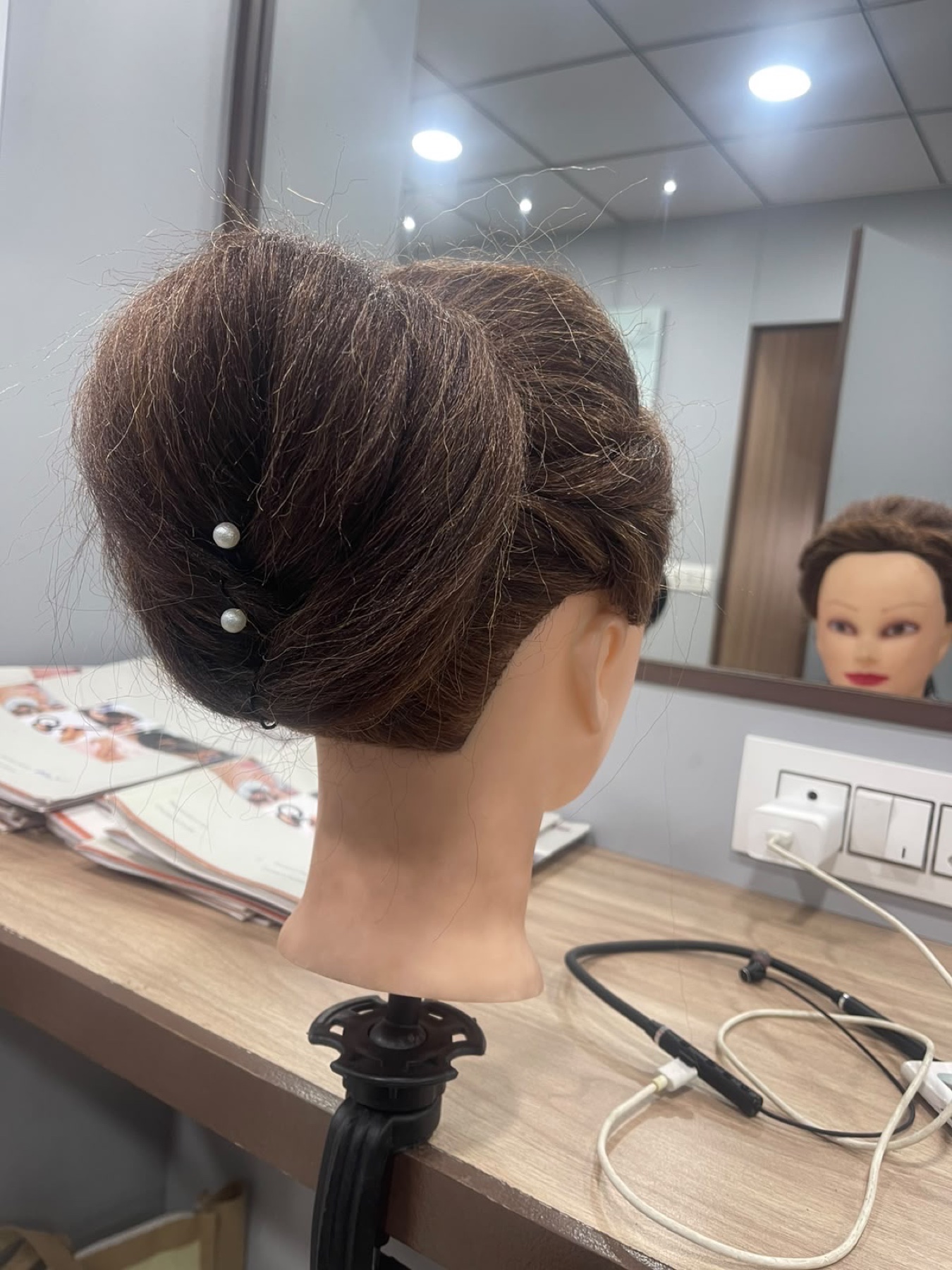 Classic pearl-pinned chignon hairstyle shown from the back